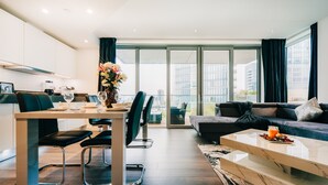 A modern living room with a dining area, large windows, and a view of the city. - LUX Aldgate Apartment I Central London Zone 1 (London)