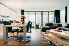Een moderne woonkamer met een eetgedeelte, grote ramen en uitzicht op de stad.