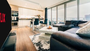 A modern living room with a sofa, coffee table, and a view of the city through large windows. - LUX Aldgate Apartment I Central London Zone 1 (London)