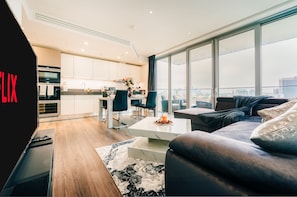 Een moderne woonkamer met een bank, salontafel en uitzicht op de stad door grote ramen.