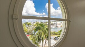 Una ventana redonda con vista a un puerto deportivo, barcos y edificios.