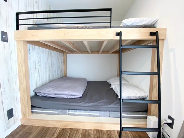 A bunk bed with a wooden frame, a mattress, pillows, and a ladder. - Seaside Garden Nishiizu 1 (Nishiizu)
