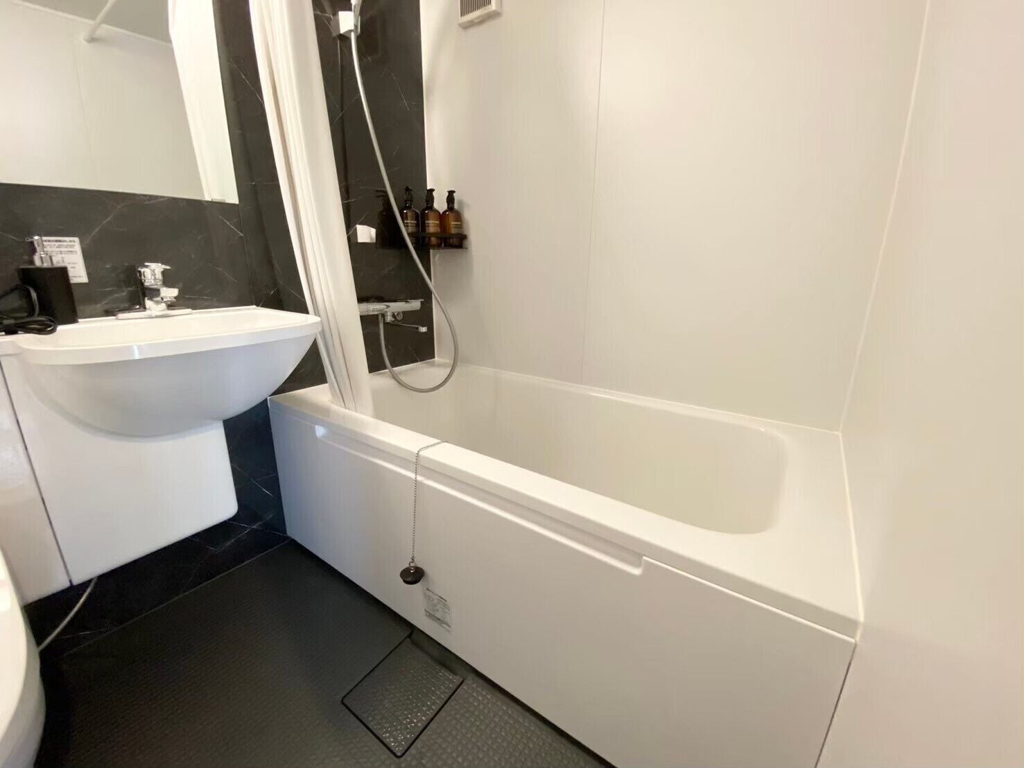 Une salle de bain avec une baignoire blanche, un lavabo et un espace douche.