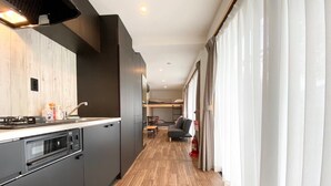 A modern kitchen with dark cabinetry, a built-in oven, and a wooden countertop. - Seaside Garden Nishiizu 1  (Nishiizu)