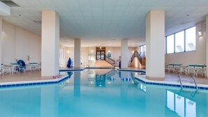 Ein großer Innenpool mit klarem Wasser, umgeben von weißen Wänden und Säulen, mit einer Treppe, die zu einer erhöhten Ebene führt.