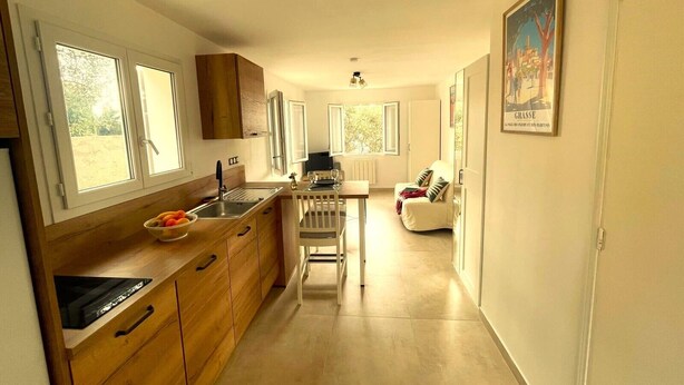 Eine schmale Küche mit Holzausstattung, ein Essbereich mit Tisch und Stühlen sowie ein Sofa.