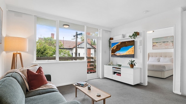 A modern living room with a sofa, coffee table, TV, and artwork. - St Kilda Retreat Near Beach & Cafes (Melbourne)