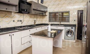 Een keuken met een gasfornuis, een inbouwoven, een wasmachine en een raam met uitzicht.