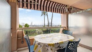 Ein Balkon mit Tisch und Stühlen, Blick aufs Meer und eine Palme.