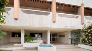 Ein modernes Gebäude mit der Aufschrift 'Espace 2000', das einen großzügigen Eingangsbereich, eine Wasseranlage und einen Balkon mit Geländer bietet.