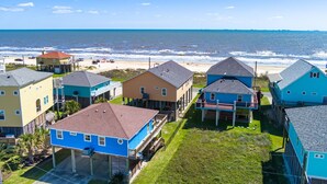 A coastal residential area with houses, a beach, and a clear sky. - Crystal Blue - 2nd Row - Easy Beach access, fenced yard, steps to the beach! (Crystal Beach)