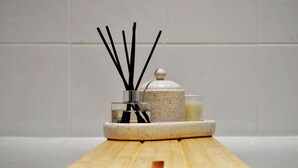 A bathroom with a wooden vanity, a glass jar with black sticks, and a small container with a lid. - Hertford Flat 14 (London)