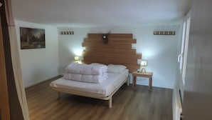 A bedroom with a wooden headboard, a bed with white bedding, two bedside lamps, and a painting on the wall. - Cottage 200 m from Lac des Settons (Montsauche-les-Settons)