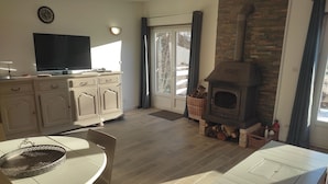 A living room with a fireplace, a television, and a dining area. - Cottage 200 m from Lac des Settons (Montsauche-les-Settons)