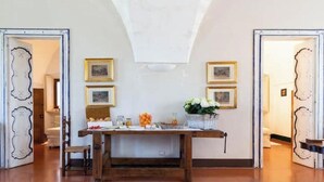 Ein Essbereich mit einem Holztisch, Stühlen, gerahmten Bildern an der Wand und einer Vase mit Blumen.