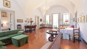Ein geräumiger Raum mit einem grünen Sofa, einem Esstisch mit Stühlen und einer Chandeliebre.