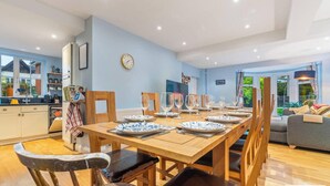Uma sala de jantar com mesa de madeira posta para seis pessoas, rodeada por cadeiras.