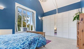 Une chambre à coucher avec un lit, une fenêtre, une armoire et une plante.