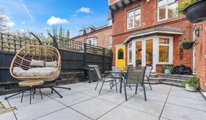 A patio with outdoor furniture, a hanging chair, and a brick house with a bay window. - Rachel`s House with Parking! (Leicester)