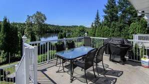 A balcony with a table and chairs, overlooking a lake and forest. - L`échappée du Lac-Saint-Jean (Lac-Saint-Jean-Est Regional County Municipality)