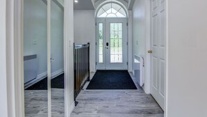 A hallway with a dark carpet, white walls, and a large arched window. - L`échappée du Lac-Saint-Jean (Lac-Saint-Jean-Est Regional County Municipality)