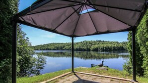 A gazebo with a view of a calm lake and forest. - L`échappée du Lac-Saint-Jean (Lac-Saint-Jean-Est Regional County Municipality)