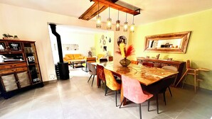 Uma sala de jantar com uma mesa grande, cadeiras, teto de madeira e lareira.