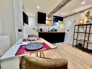 Una cocina moderna con una mesa de comedor, sillas y una estantería negra.