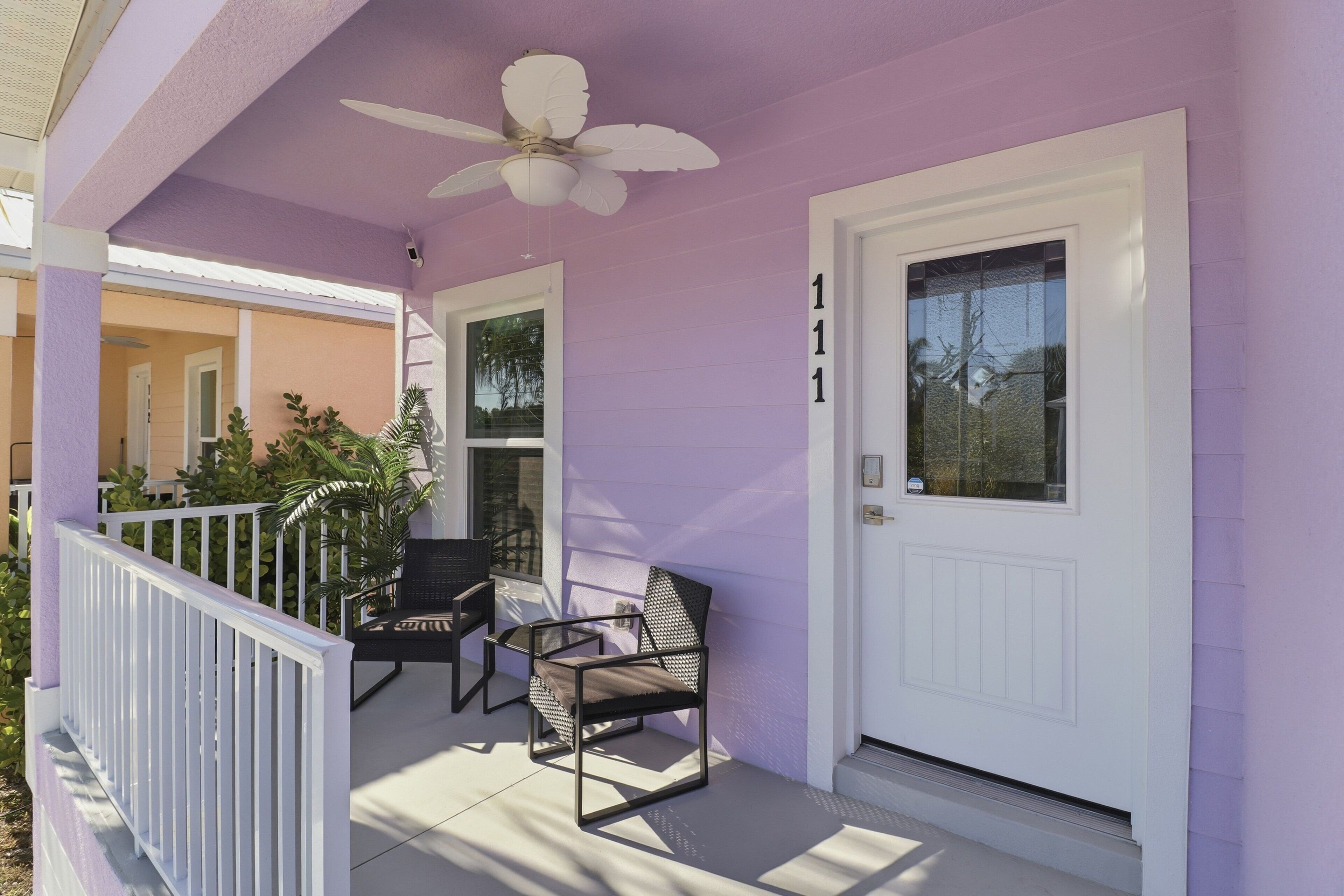 Ein Haus mit violetten Wänden, einer weißen Tür und der Hausnummer 111.