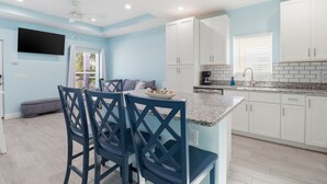 A modern kitchen with white cabinets, a granite countertop, and a built-in oven. - New! Charming Lilac Cottage 111 (Punta Gorda)