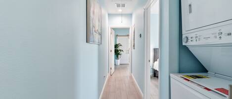 A laundry room with a washing machine, a dryer, and a door leading to another room.