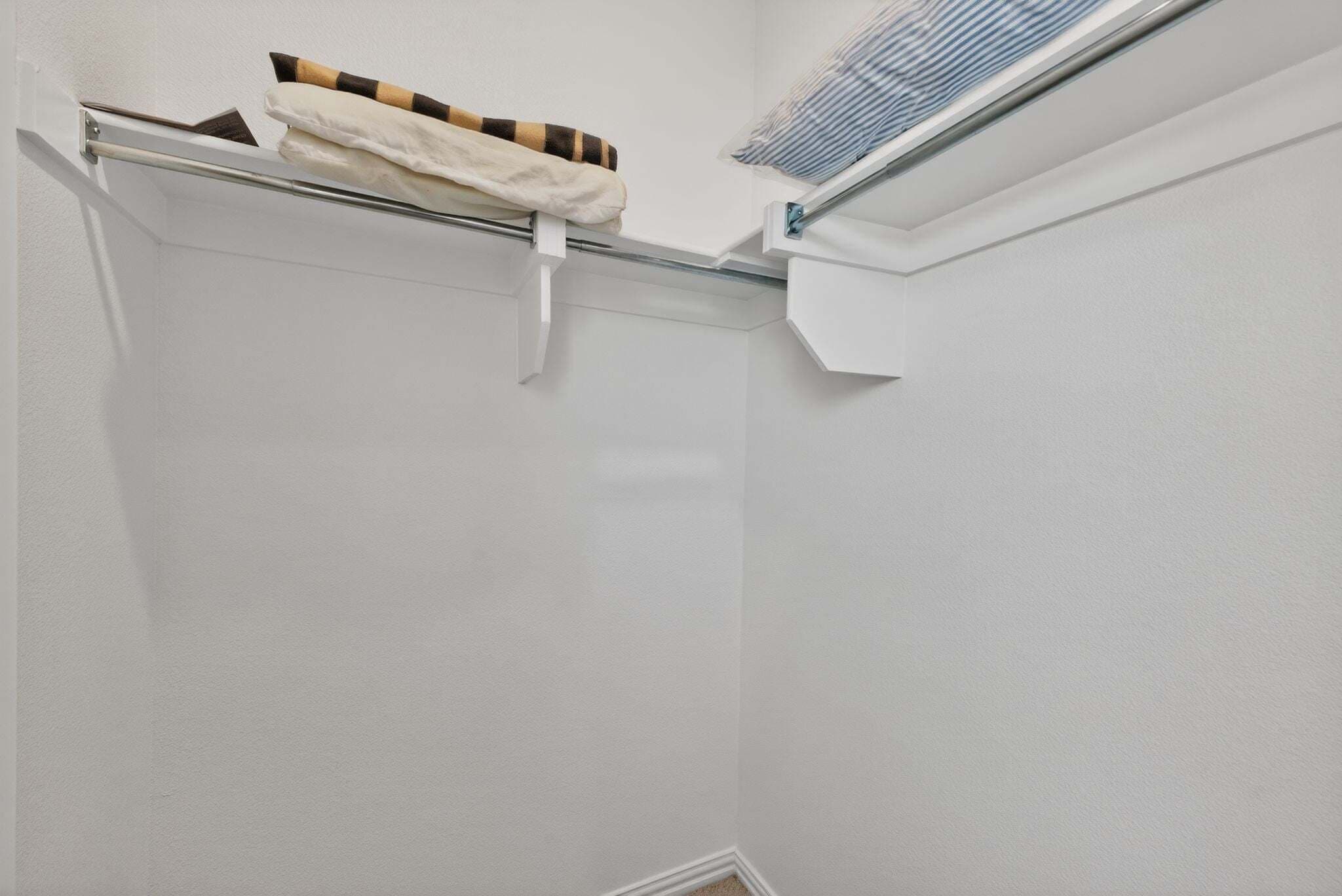 A corner of a room with a towel rack, a vent, and a white wall.