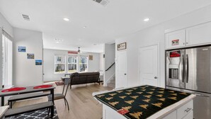 Eine moderne Küche mit einem Edelstahlkühlschrank, einem Essbereich mit Tisch und Stühlen sowie einer Couch im Hintergrund.