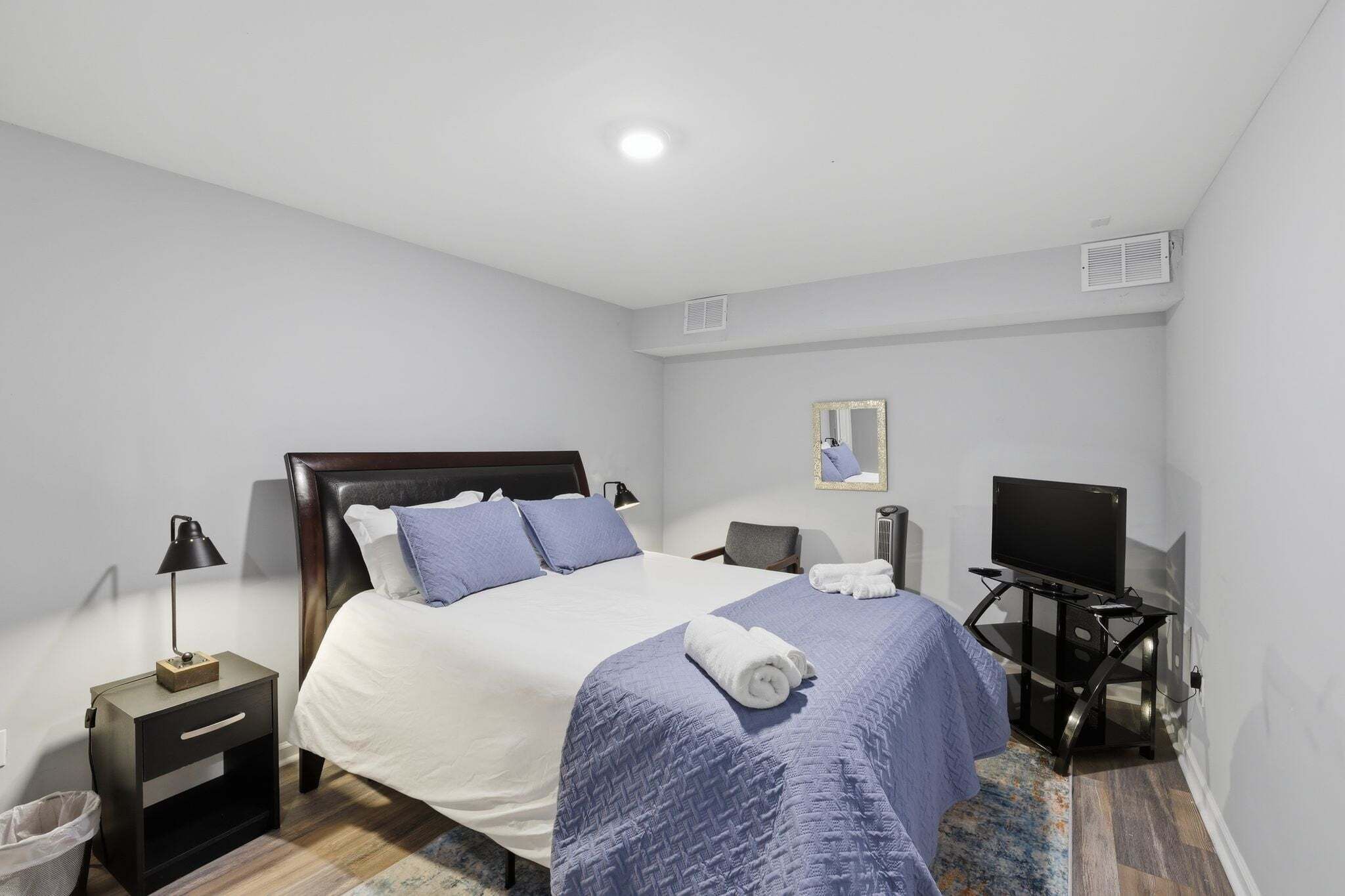 Un dormitorio con cama, televisión, escritorio y silla.