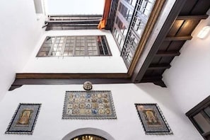 Ein Zimmer mit hohen Decken, einem Oberlicht und einer Wand mit gerahmten Kunstwerken.