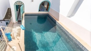 Une petite piscine à eau claire, dotée d’une terrasse en bois et d’un porte-serviettes.