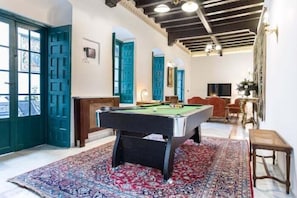 Ein Zimmer mit Billardtisch, einem gemusterten Teppich und einer Tür mit blauem Dekor.