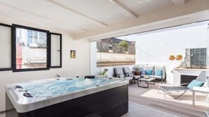 Un espace moderne aménagé à l’extérieur avec un bain à remous et des sièges, offrant une vue sur le paysage urbain.