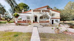 Uma casa de dois andares com fachada de pedra, um alpendre coberto e um pequeno jardim.
