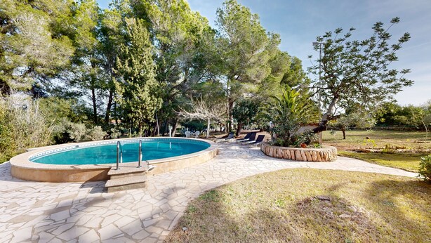 Piscina com azulejos de pedra, rodeada por árvores e um caminho de pedra.