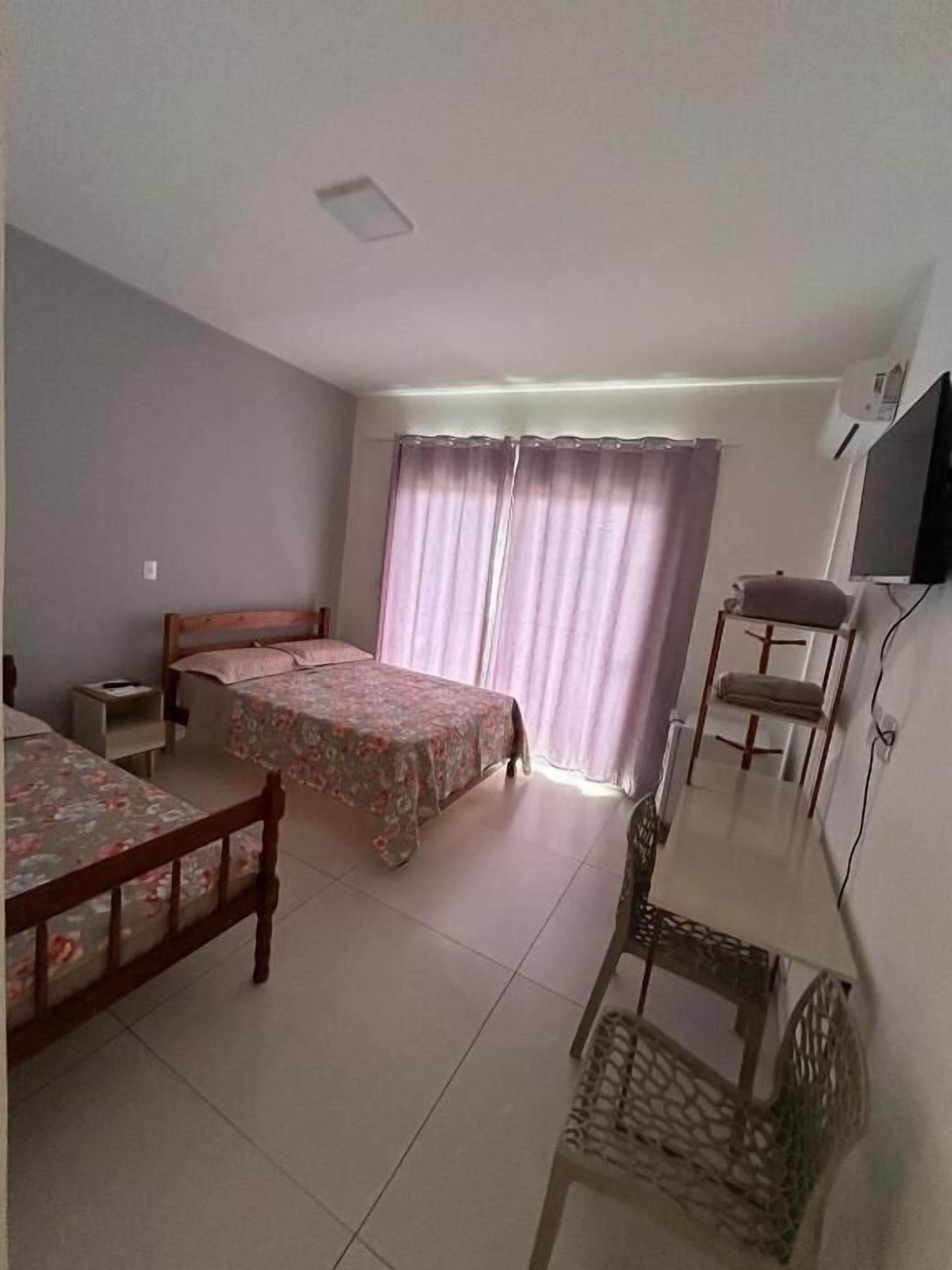 A bedroom with two beds, a desk, a chair, and a TV.