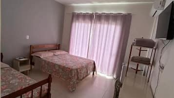 A bedroom with two beds, a desk, a chair, and a TV.