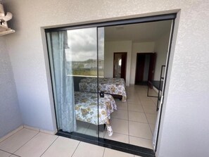 Una habitación con dos camas, una puerta corrediza de vidrio y vistas al exterior.
