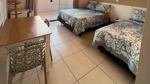 A hotel room with two beds, a wooden table, a chair, a window with curtains, an air conditioning unit, and a painting on the wall. - Pousada Barra Coast (Barra Velha)