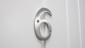 En nummer 6 i metal på dørskiltet.