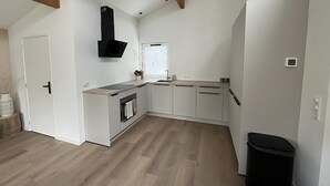 Una cucina moderna con mobili bianchi, una cappa aspirante nera e una finestra.
