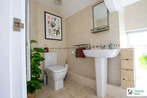 A bathroom with a toilet, sink, and a framed botanical print on the wall. - The Bird`s Nest - 1 bed flat (Cornwall)