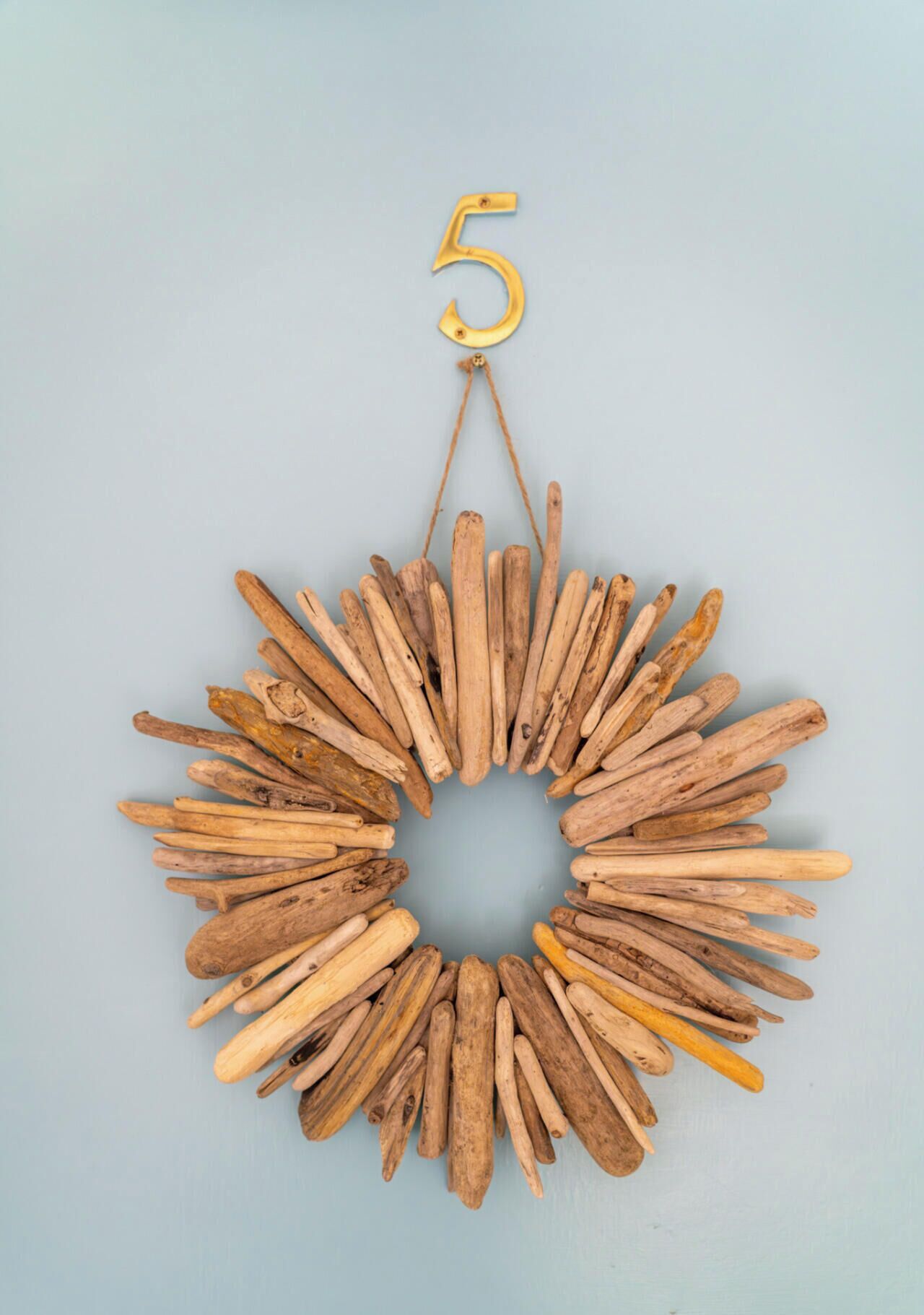 A circular wooden wall hanging with a hanging number '5' and a central hole.