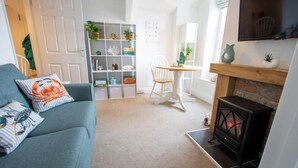 A living room with a sofa, a fireplace, a dining table, and a bookshelf.