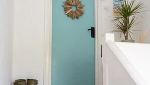 A teal door with a keyhole, a doormat with 'WELCOME' text, and a pair of green boots beside the door.